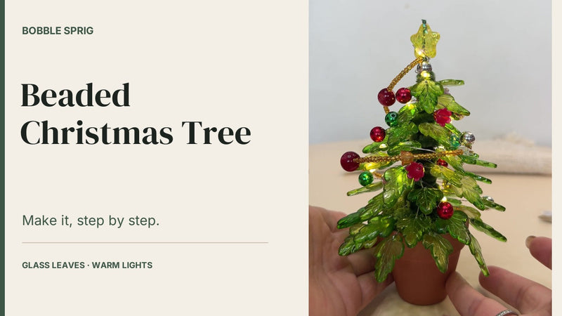Beaded Christmas tree cover: a lit glass-leaf Christmas tree in a terracotta pot, held in one hand, with the Bobble Sprig title card alongside it.
