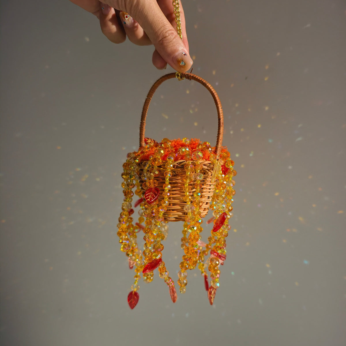 Handheld Autumn Dusk beaded basket showing its small scale and cascading autumn-colored strands