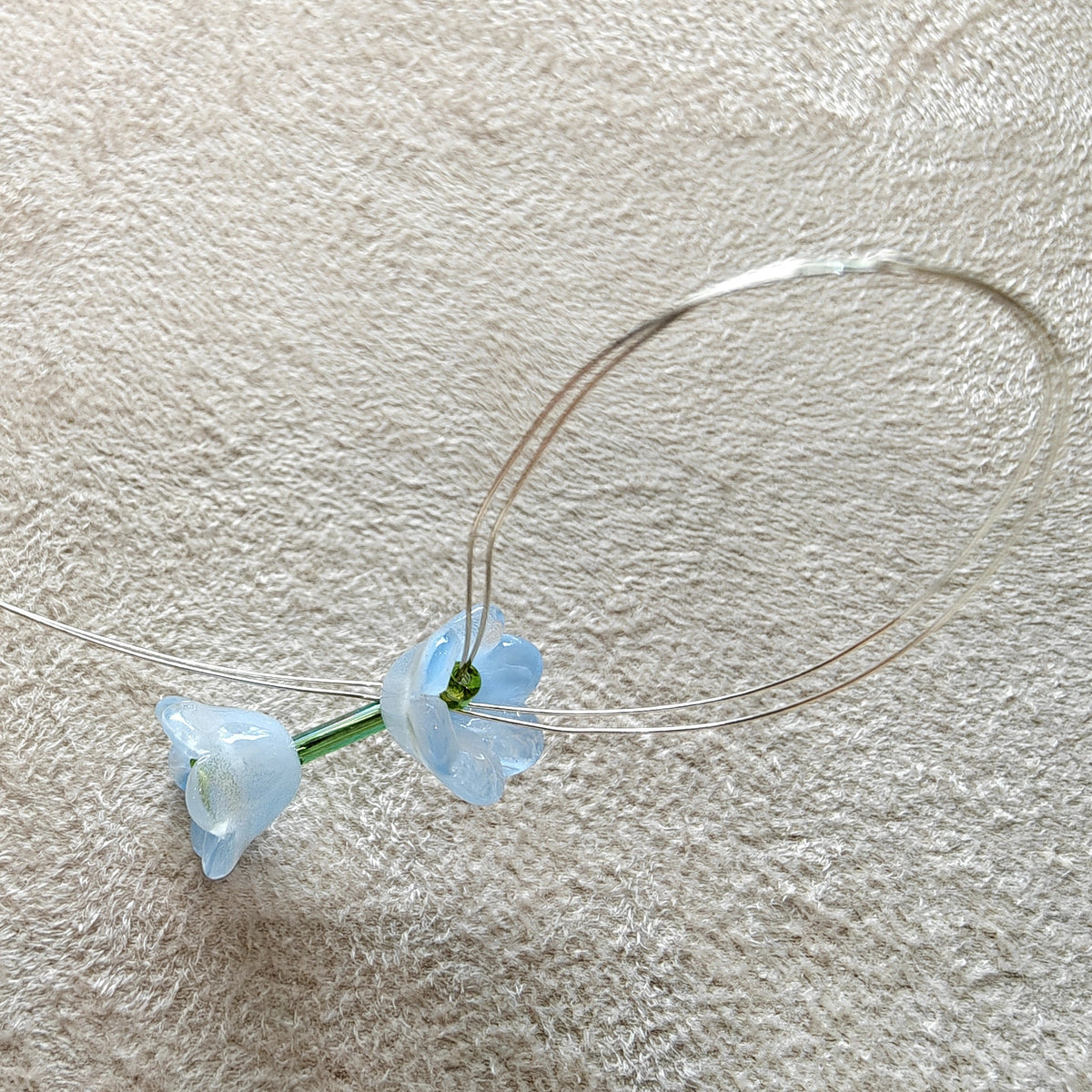 Small blue flower earrings on a textured beige surface