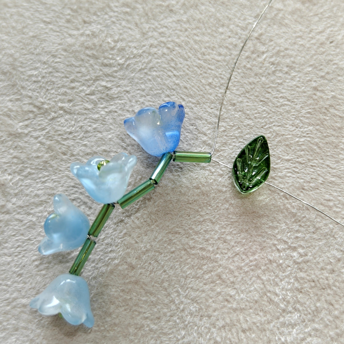 Small blue floral pendant on a string against a beige background