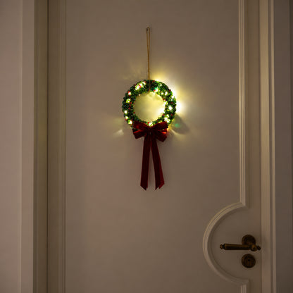 Full green glass-beaded Christmas wreath with warm lights and a burgundy velvet bow hanging on a cream door at night.