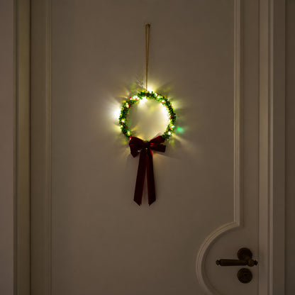 Large slim green glass-beaded Christmas wreath glowing with warm lights and a burgundy velvet bow on a cream door.