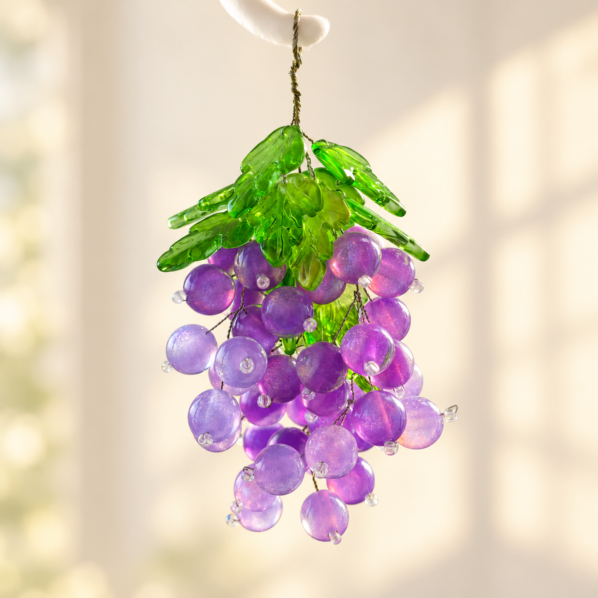 Close-up of translucent purple grape beads, green leaf beads and fine wire