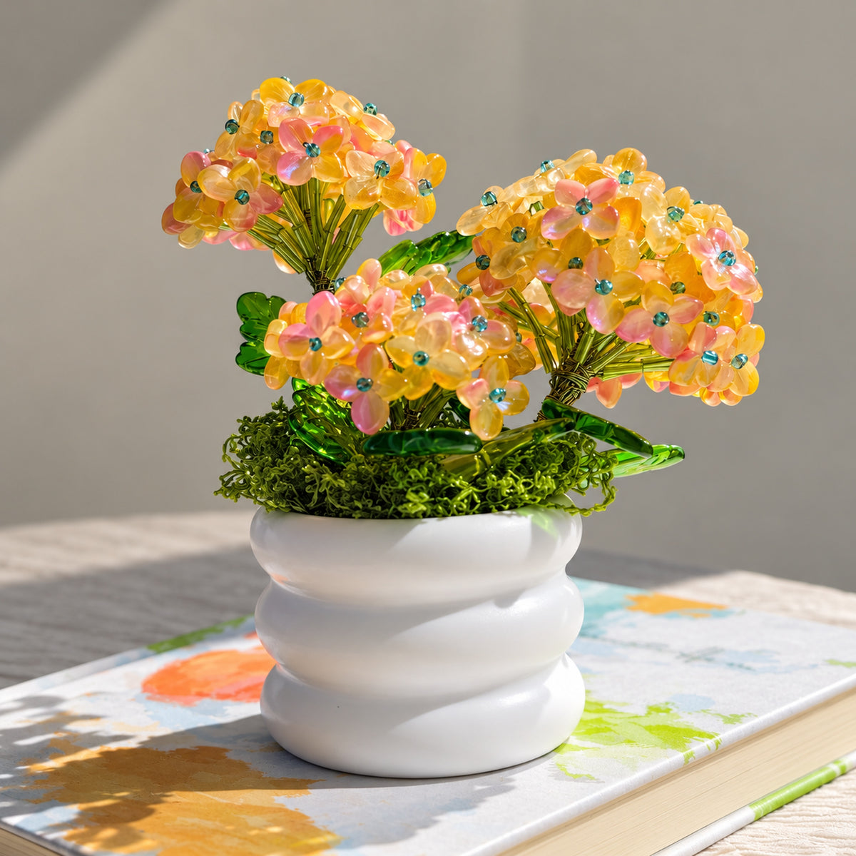 Bright view of pink and yellow beaded hydrangea in a white spiral ceramic pot