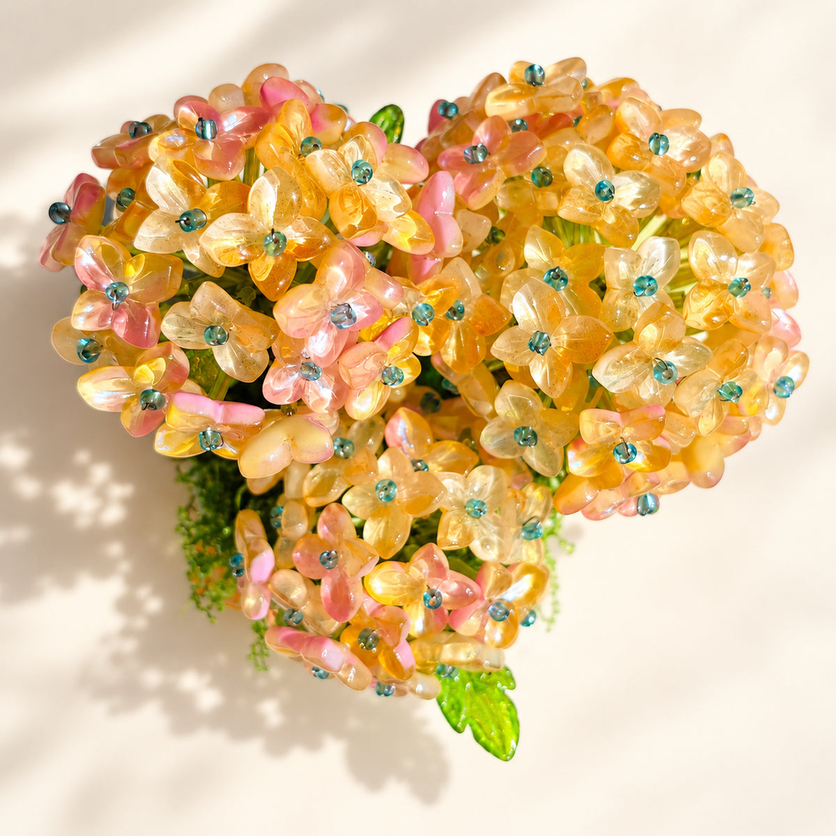Close-up of translucent pink and yellow hydrangea flower beads with teal centers.