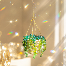Green beaded hanging ornament with a gold chain against a sparkling background