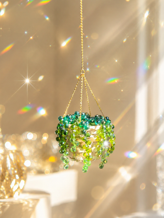Green beaded hanging ornament with a gold chain against a sparkling background