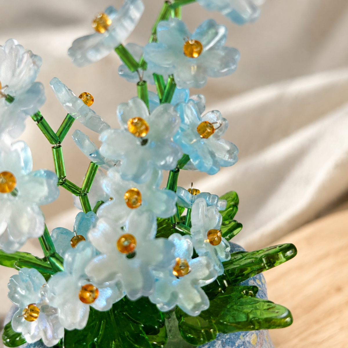 Close-up of translucent blue flower beads with gold centers and green stems