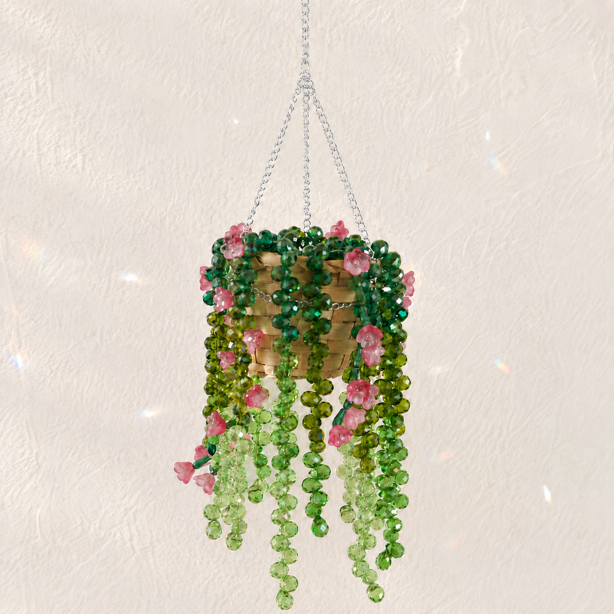 Cascading green beaded hanging plant with translucent rose pink flower beads and a silver chain