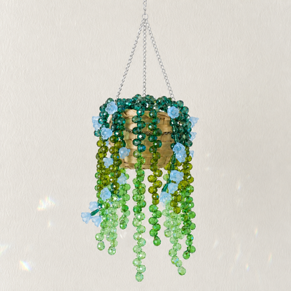Cascading green beaded hanging plant with pale blue flower beads and a silver chain