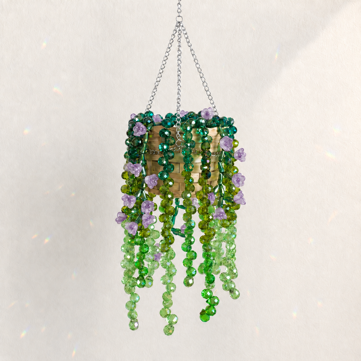 Cascading green beaded hanging plant with translucent amethyst purple flower beads and a silver chain