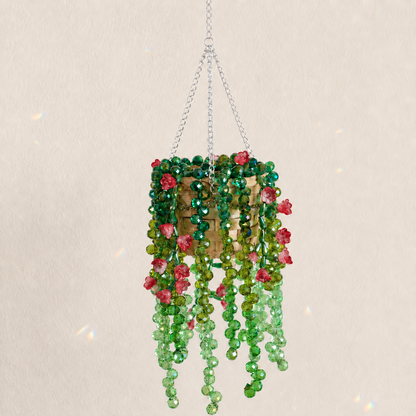 Cascading green beaded hanging plant with translucent ruby red flower beads and a silver chain