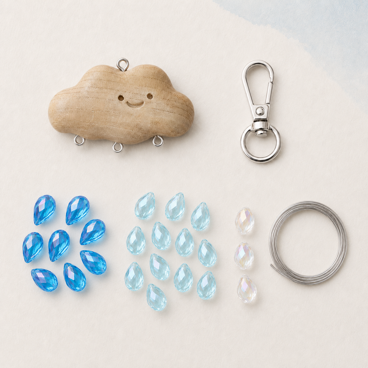 Cloud charm DIY kit with deep lake-blue, light lake-blue, and transparent AB teardrop glass beads, wooden cloud connector, silver lobster clasp, and coiled steel wire