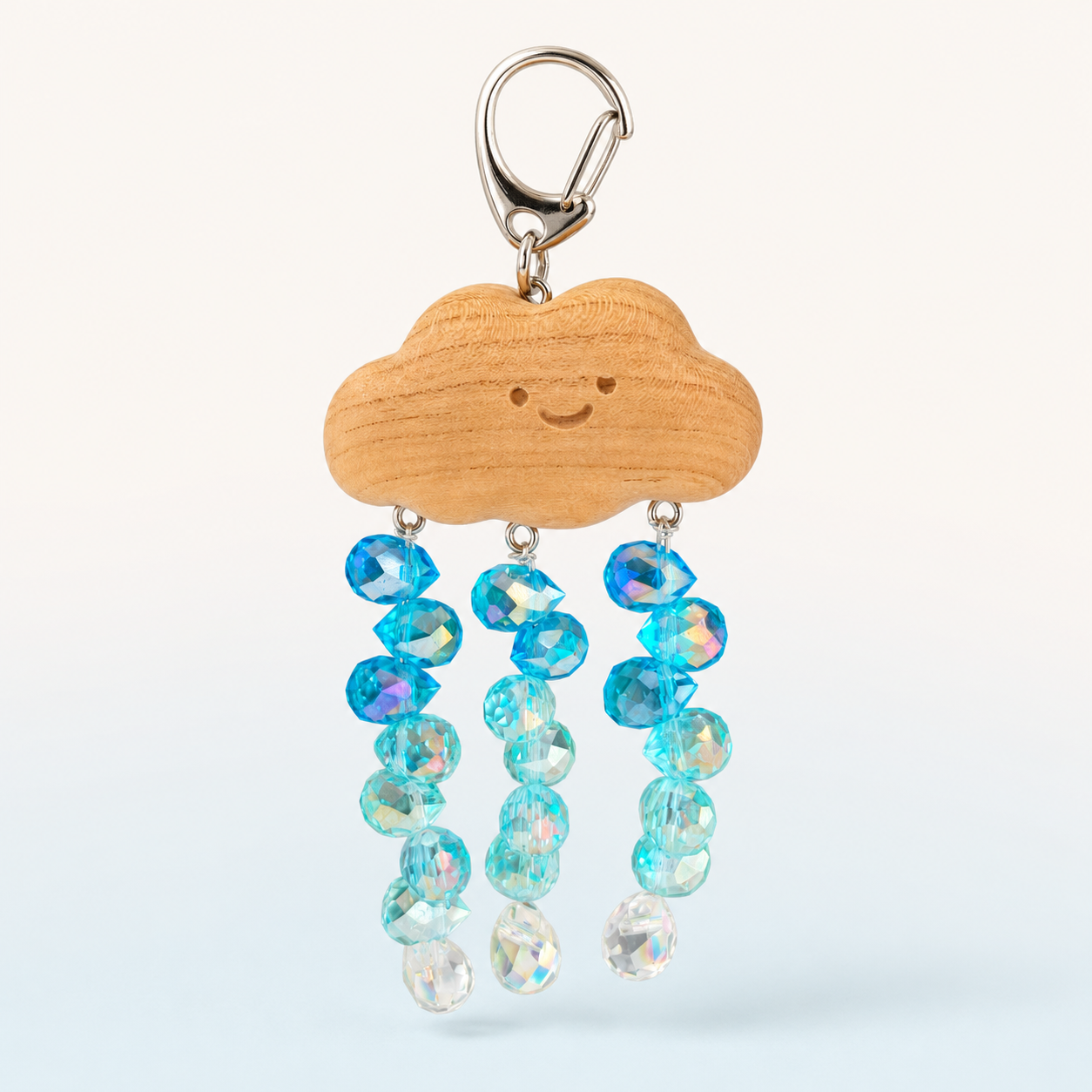 Cloud and crystal rain beaded charm with a smiling wooden cloud, silver clasp, and three strands of blue and clear faceted glass beads