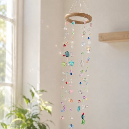 Colorful beaded hanging mobile suncatcher beside a sunny window and green plant