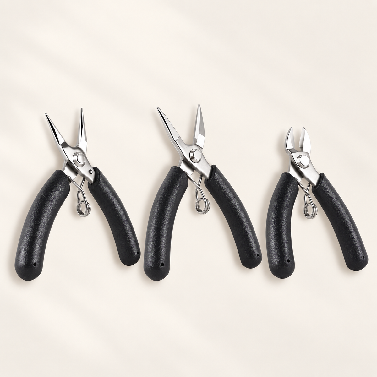 Three mini stainless steel jewelry tools with black handles: round-nose pliers, chain-nose pliers, and diagonal cutters