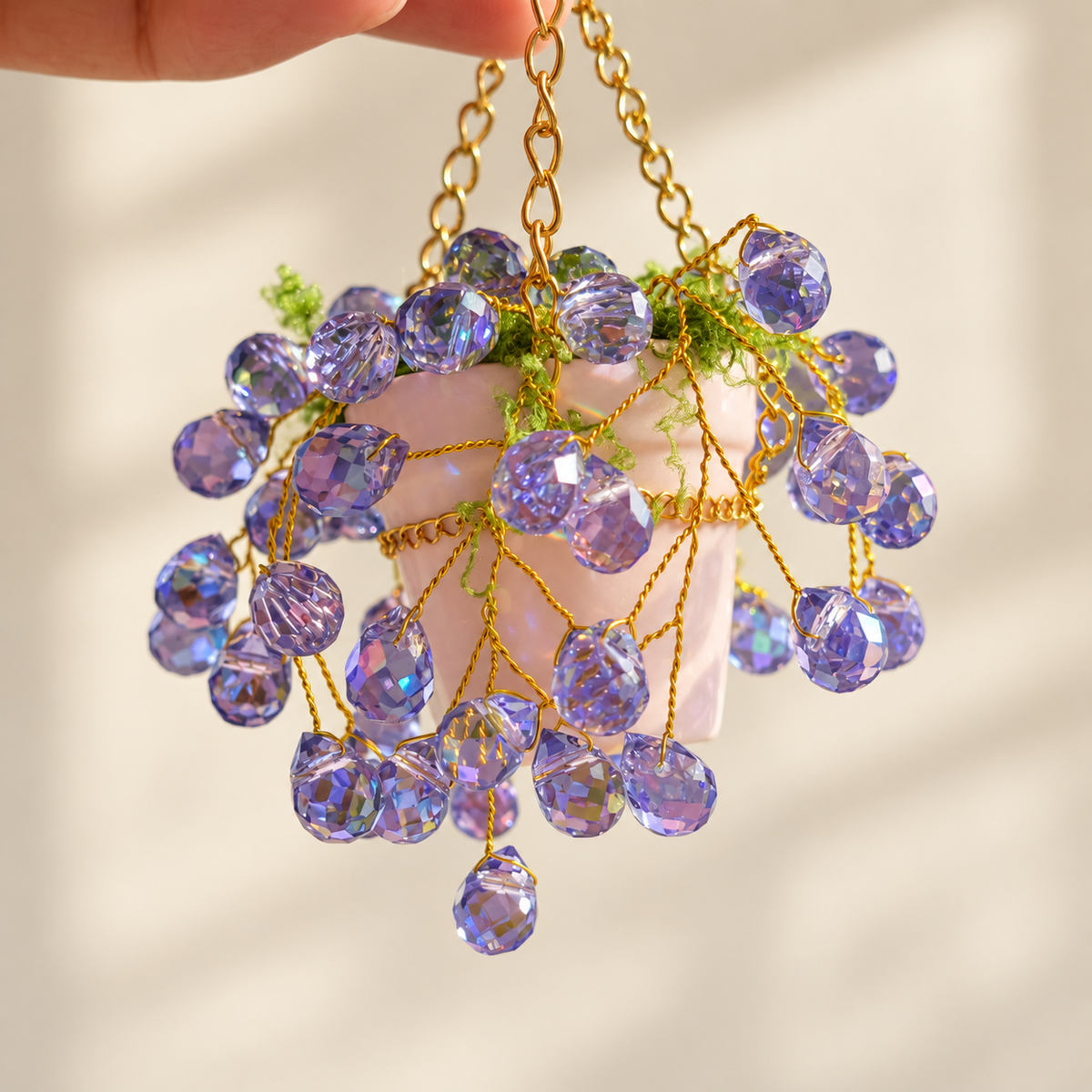 Close-up of purple faceted beads, gold-colored copper wire and the ceramic hanging pot
