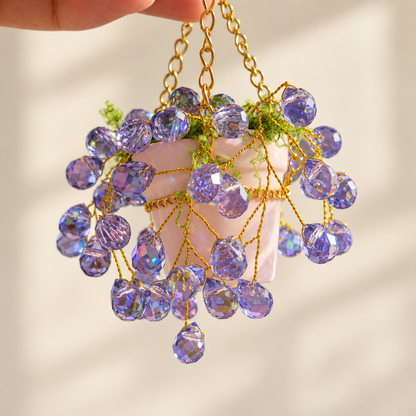 Close-up of purple faceted beads, gold-colored copper wire and the ceramic hanging pot
