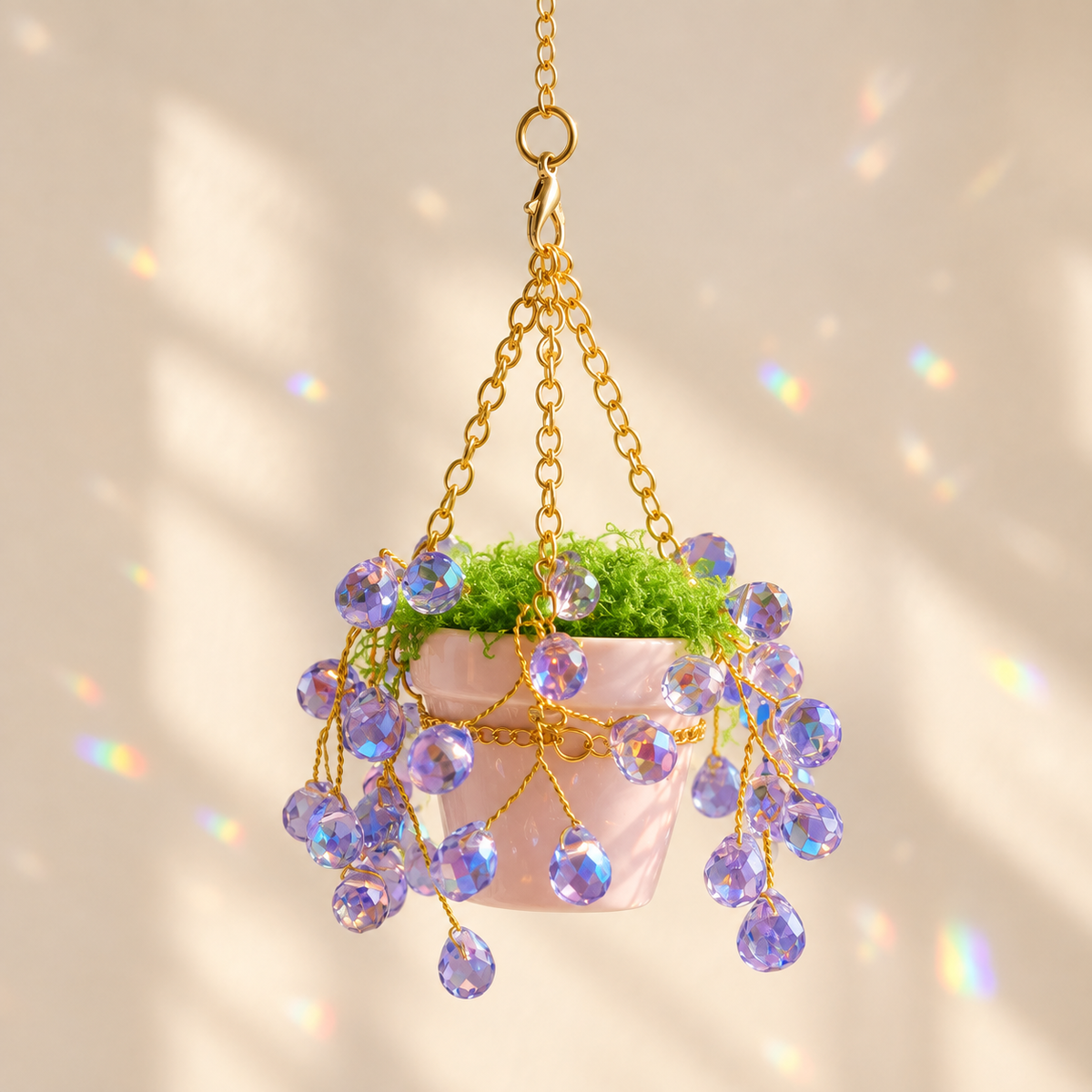 Upright miniature ceramic pot with trailing purple faceted beads and gold hanging chains in sunlight