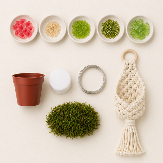 DIY kit materials with pink flower beads, green seed and bugle beads, Czech glass leaves, wire, pot, foam, faux grass, and a white woven pouch
