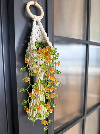 Flower vine beaded wall hanging with orange blooms cascading from a cream woven pouch